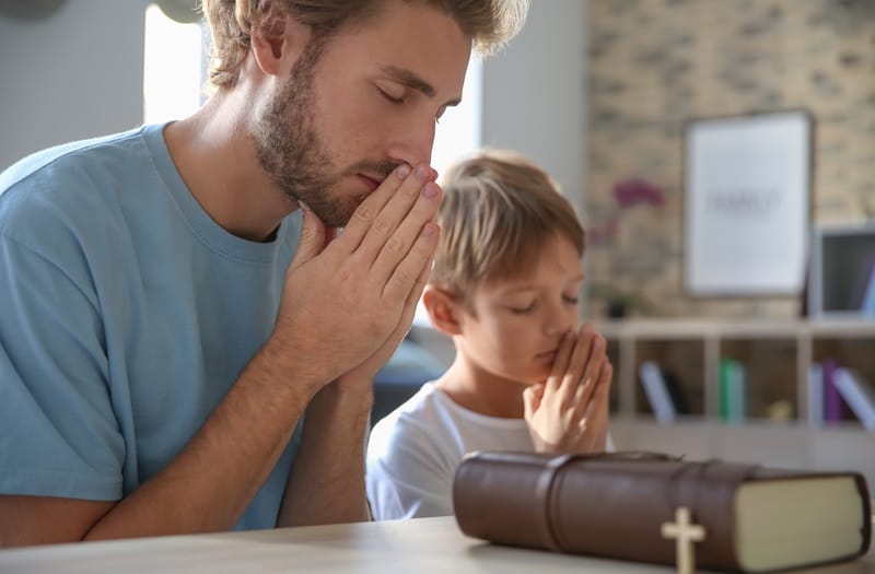 happy fathers day dad and son praying together